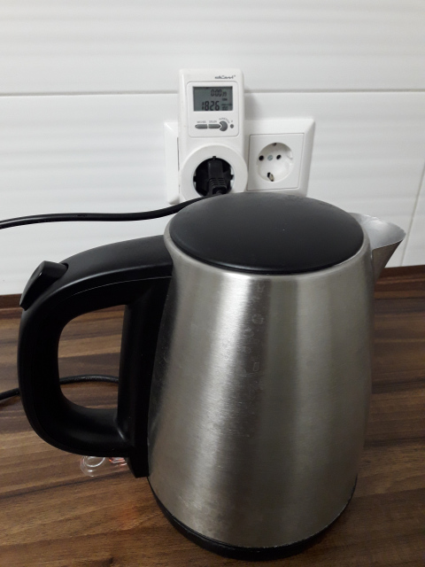 Ein Wasserkocher ist an ein Strommessgerät angeschlossen. Es zeig 1826W an.